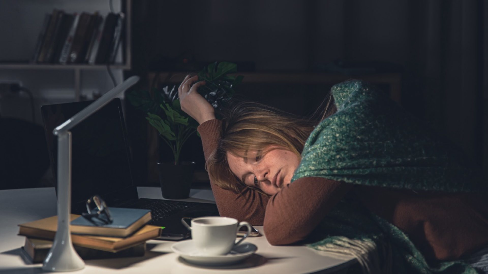 A tired young woman at the workplace wants to sleep late at night, insomnia, anxiety.